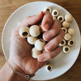 hand holding 8 round wood beads, each bead larger than the width of the fingers