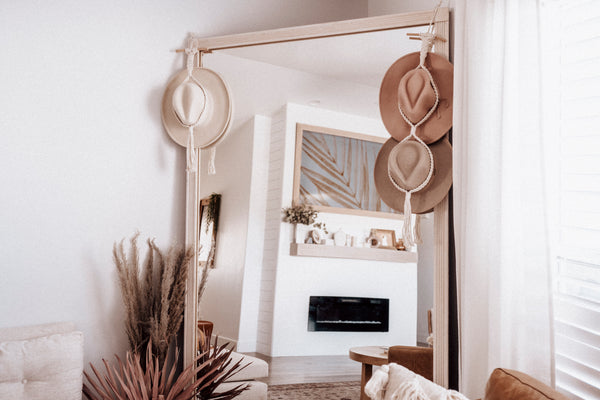 boho room decor withe hat collection displayed on large floor mirror