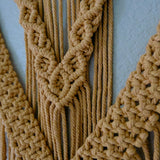 Detailed close-up of macrame fiber art featuring textured knots and fringe accents