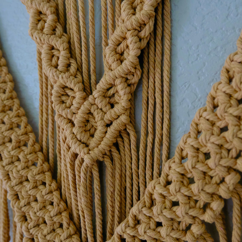 Detailed close-up of macrame fiber art featuring textured knots and fringe accents