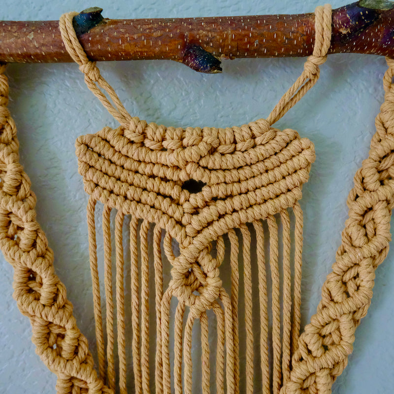 Detailed close-up of macrame fiber art featuring textured knots and fringe accents