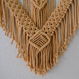 Detailed close-up of macrame fiber art featuring textured knots and fringe accents