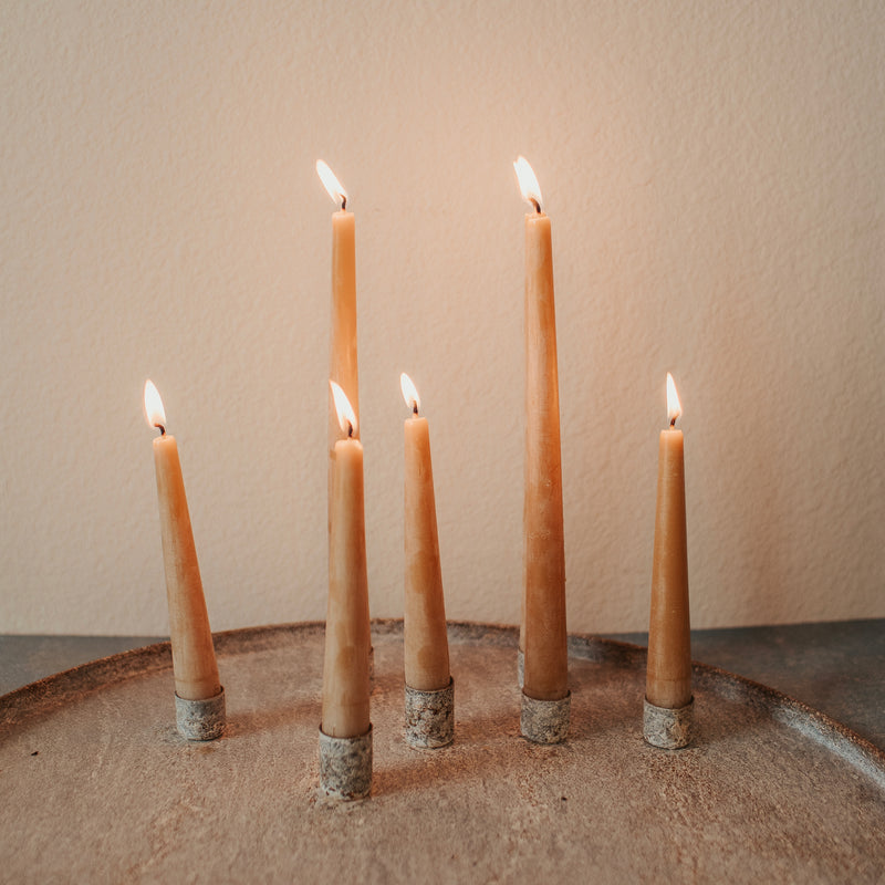 Set of 6 inch and 10 inch hand-poured honey beeswax taper candles burning, showing warm glow