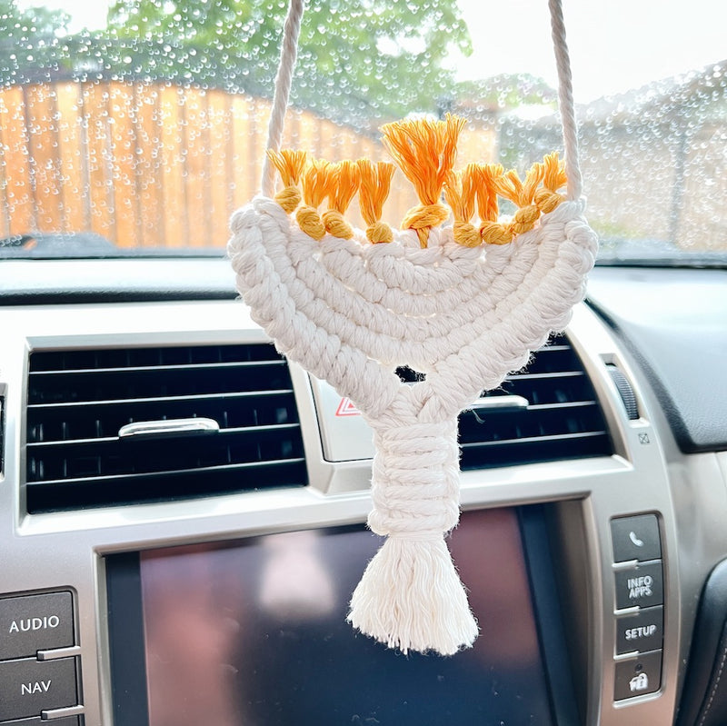 white hanukkai ornament hanging in a car's rear view mirror