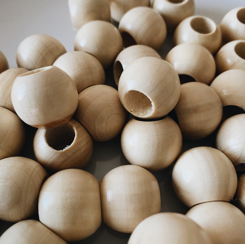 20mm round wood beads are finished and have a subtle sheen of light bouncing off them